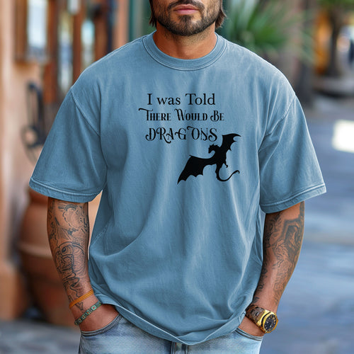 Person wearing a Washed Denim T-shirt with a Renaissance Faire-inspired design that reads “I Was Told There Would Be Dragons” in medieval-style fonts. The graphic features a bold silhouette of a flying dragon, perfect for fantasy lovers and fairgoers who enjoy whimsical and mythical-themed apparel.
