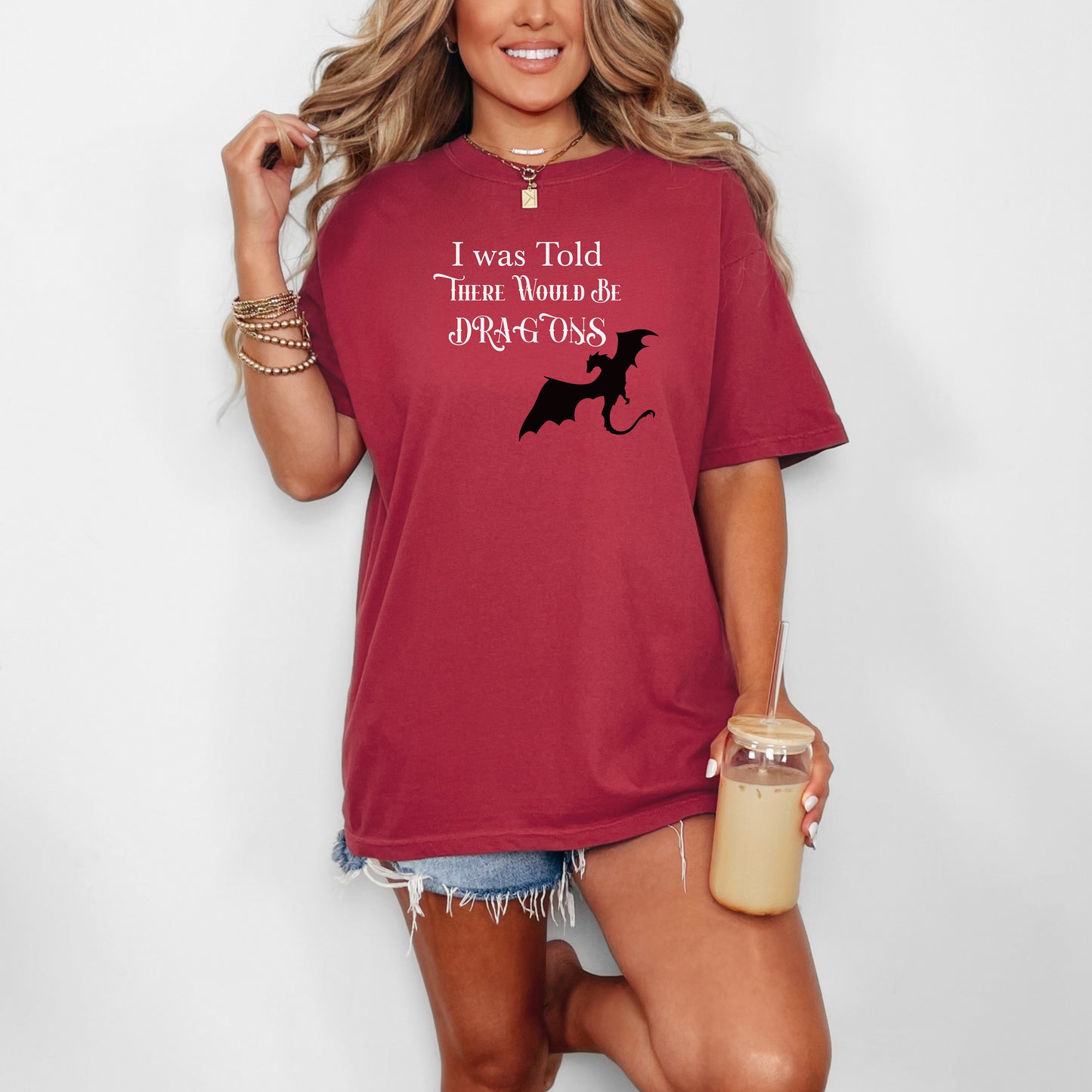 Person wearing a Chili T-shirt with a Renaissance Faire-inspired design that reads “I Was Told There Would Be Dragons” in medieval-style fonts. The graphic features a bold silhouette of a flying dragon, perfect for fantasy lovers and fairgoers who enjoy whimsical and mythical-themed apparel.