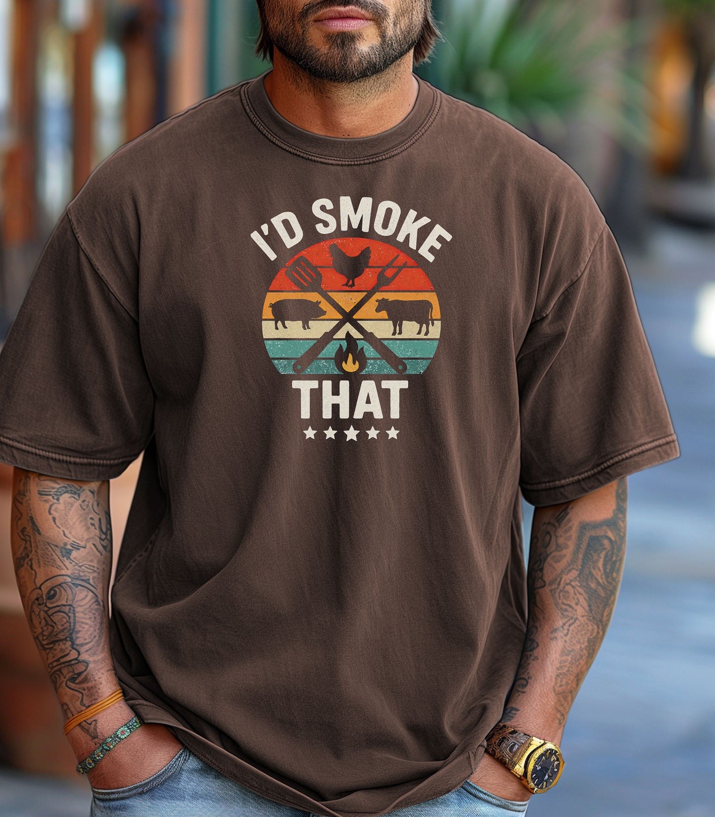 I’d Smoke That T-shirt featuring a retro sunset-style circle graphic with silhouettes of a chicken, pig, and cow, crossed grilling utensils, and a small flame. Text appears above and below the design, accented by five stars at the bottom. Printed on an espresso unisex tee, this fun BBQ-themed shirt is perfect for grill masters, smoking enthusiasts, and meat lovers who enjoy cooking with humor.