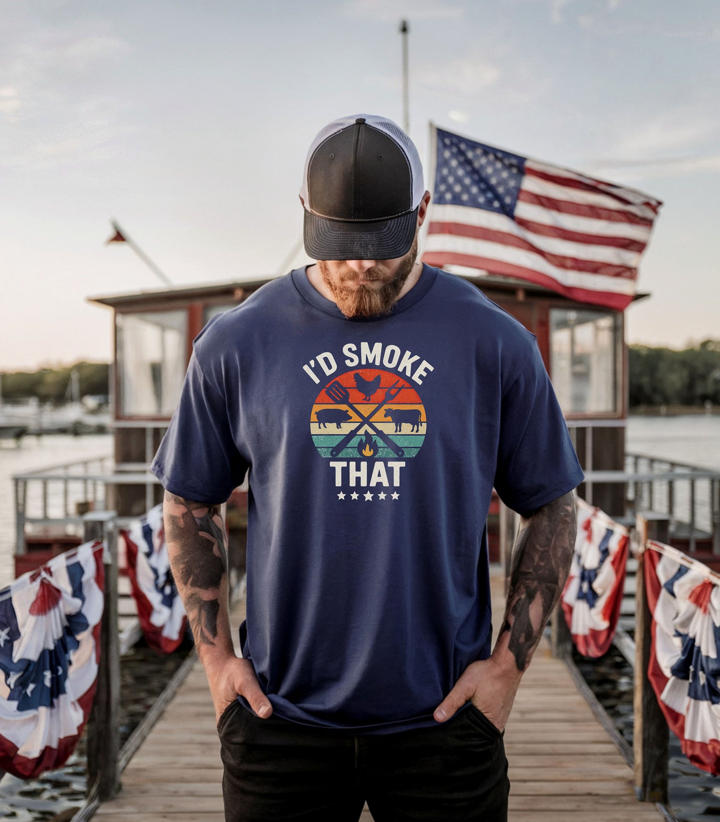 I’d Smoke That T-shirt featuring a retro sunset-style circle graphic with silhouettes of a chicken, pig, and cow, crossed grilling utensils, and a small flame. Text appears above and below the design, accented by five stars at the bottom. Printed on a true navy unisex tee, this fun BBQ-themed shirt is perfect for grill masters, smoking enthusiasts, and meat lovers who enjoy cooking with humor.