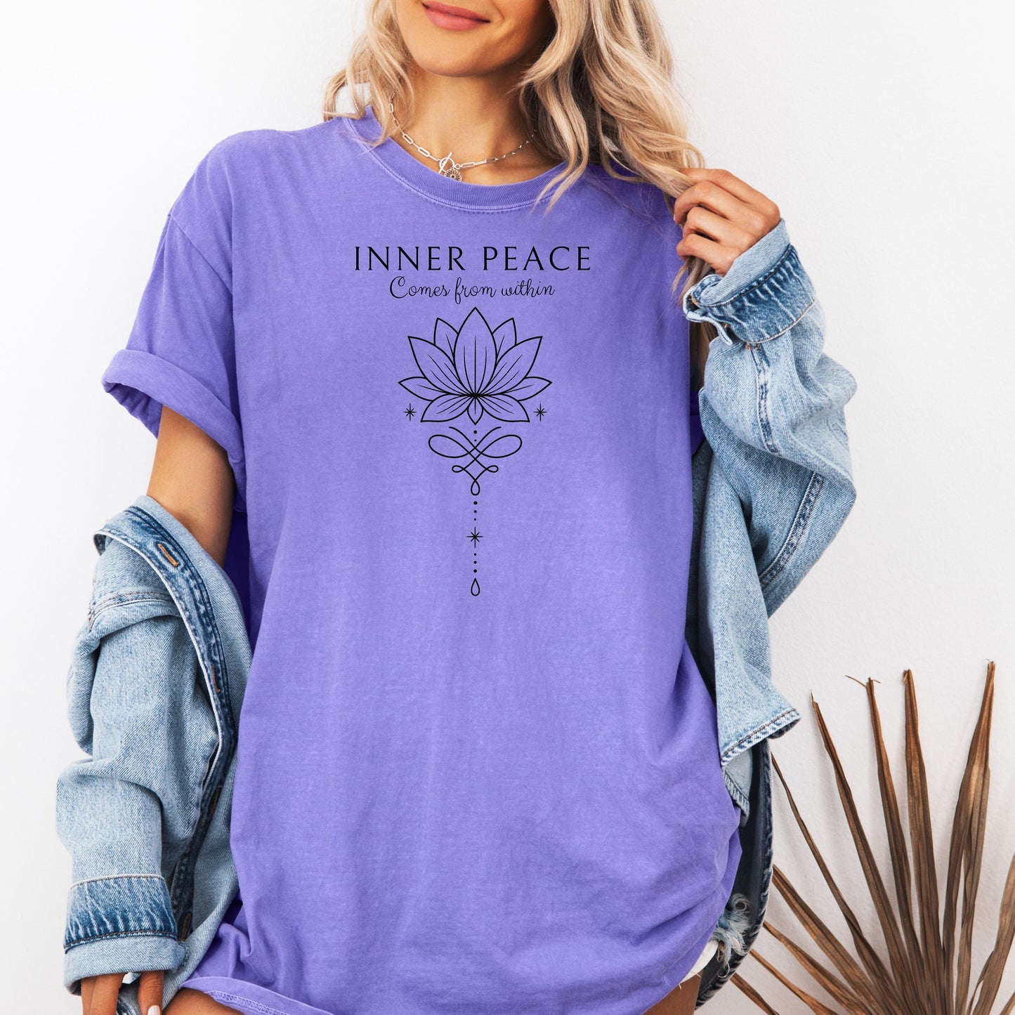Person wearing a violet T-shirt featuring an “Inner Peace Comes from Within” design with a black line art lotus flower and elegant ornamental accents. The minimalist, symmetrical artwork conveys tranquility, mindfulness, and spiritual balance, making it perfect for yoga enthusiasts, meditation lovers, and those seeking calm, positive energy in their everyday style.