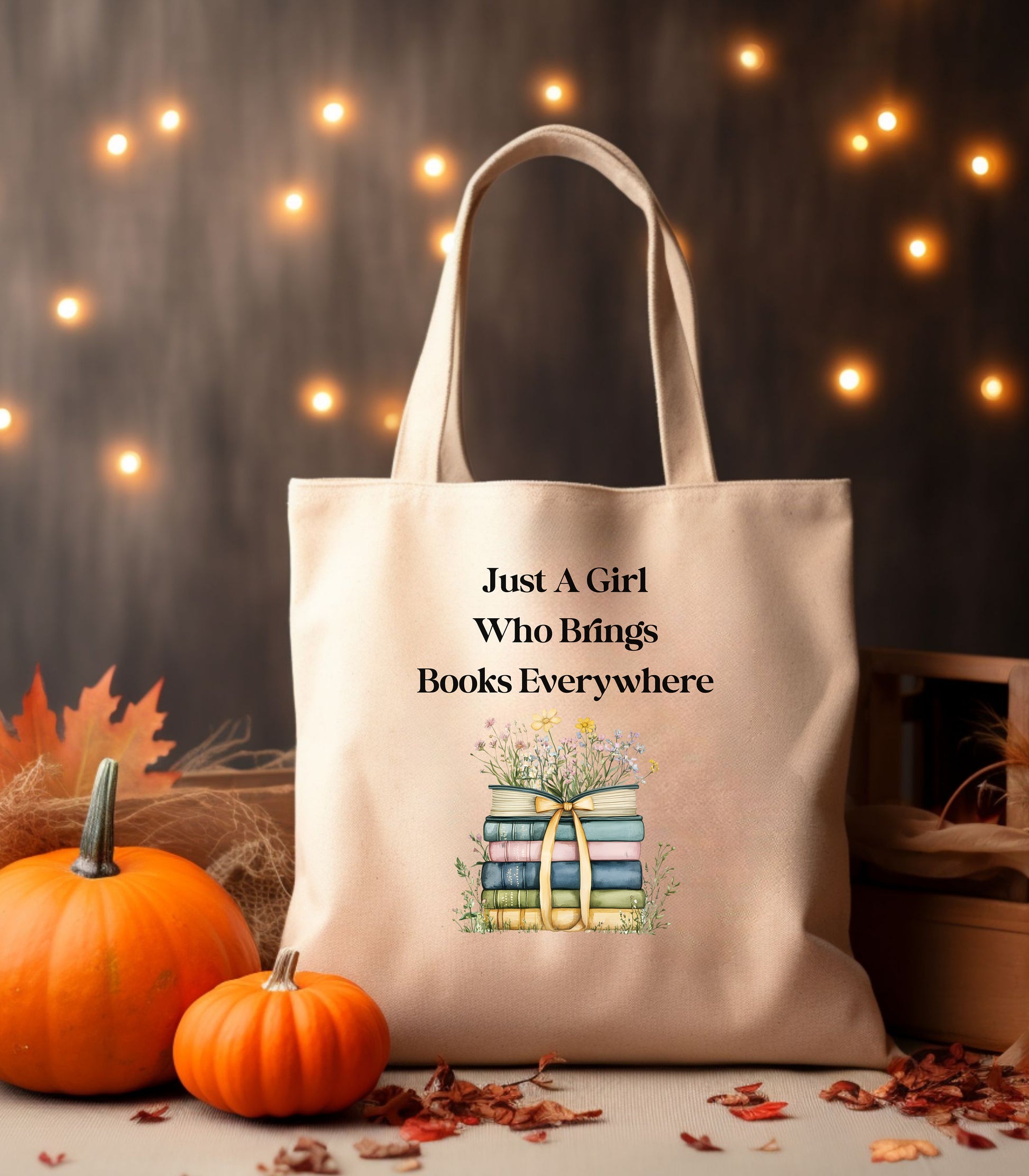 Natural tote bag with 'Just A Girl Who Brings Books Everywhere' text and book illustration, surrounded by flowers.