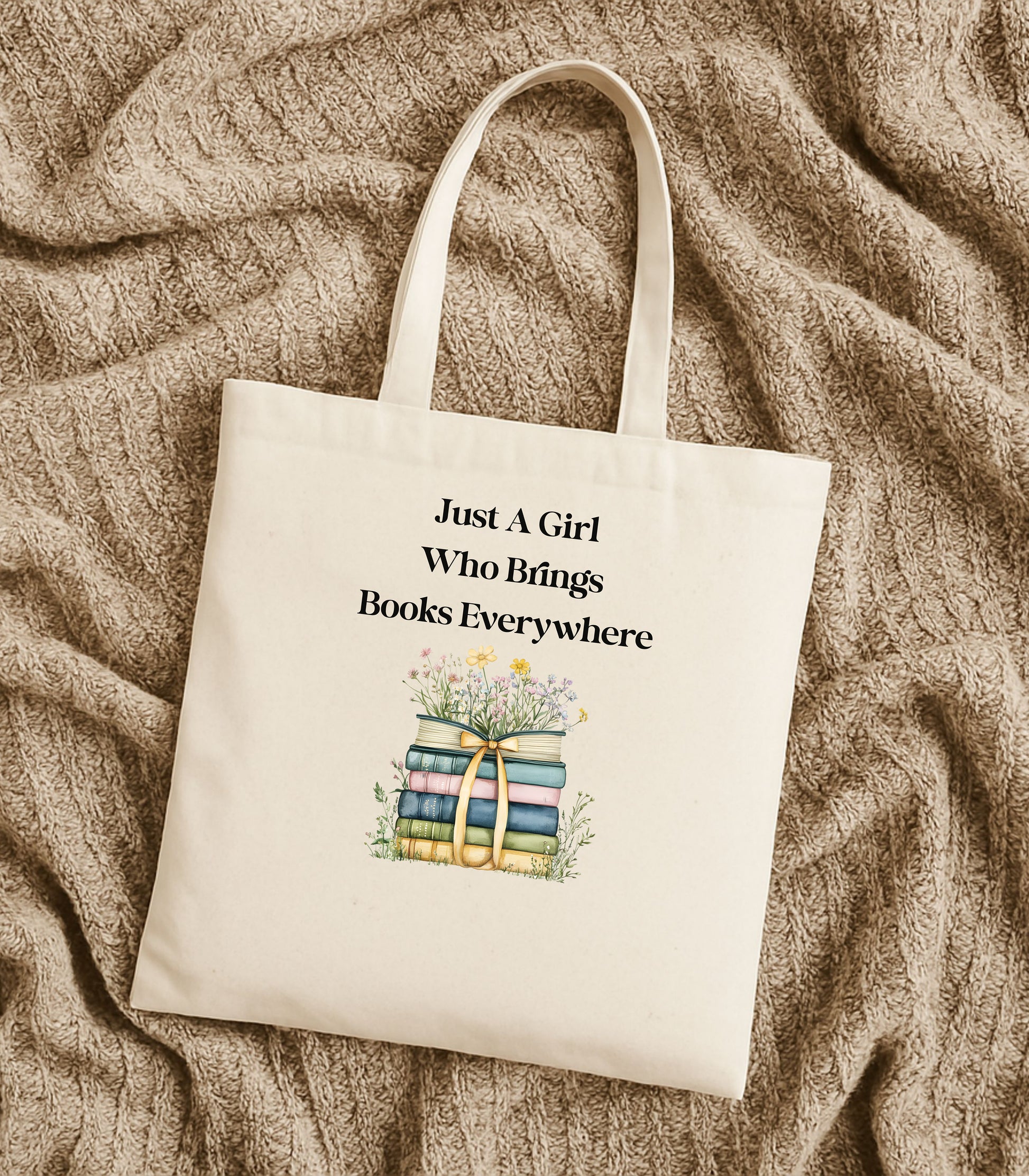 Natural tote bag with 'Just A Girl Who Brings Books Everywhere' text and book illustration, surrounded by flowers.