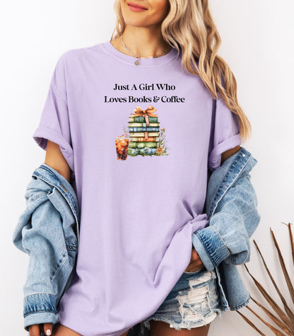 Woman wearing an Orchid t-shirt with the phrase "Just A Girl Who Loves Books & Coffee" printed above a charming stack of pastel-colored books tied with a ribbon, surrounded by fall foliage and a glass of iced coffee. A cozy and whimsical design perfect for bookworms and coffee lovers alike.