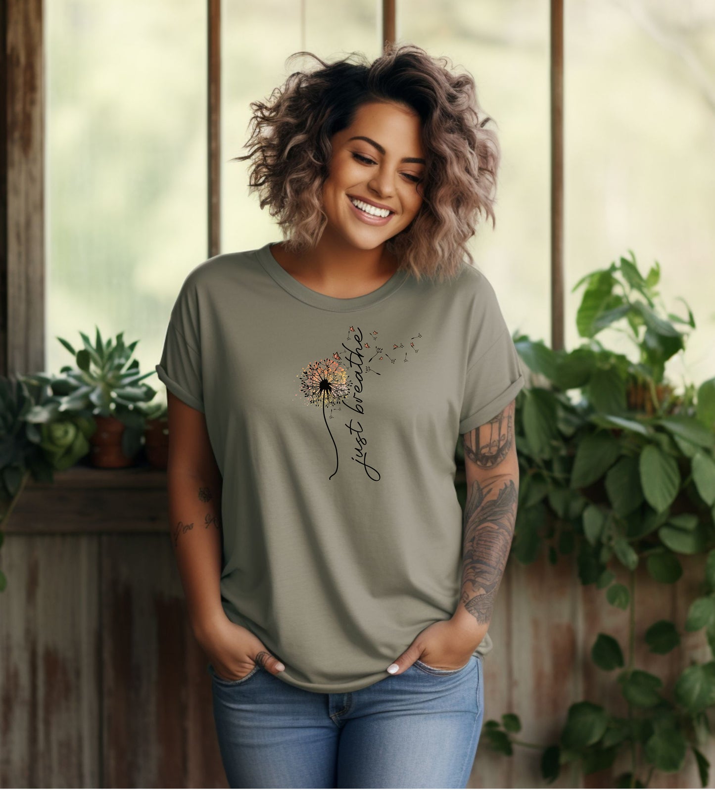 Just Breathe T-shirt featuring an artistic dandelion design with seeds blowing in the wind, transitioning into the handwritten phrase 'just breathe.' Printed on a moss unisex tee, this calming and inspirational graphic is perfect for promoting mindfulness, relaxation, and a peaceful mindset. Ideal for yoga lovers, nature enthusiasts, and casual everyday wear.