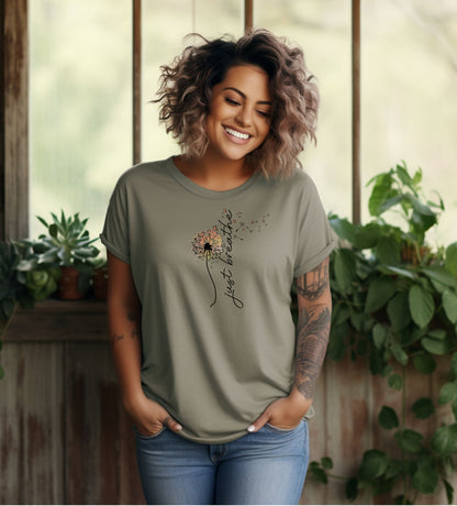 Just Breathe T-shirt featuring an artistic dandelion design with seeds blowing in the wind, transitioning into the handwritten phrase 'just breathe.' Printed on a moss unisex tee, this calming and inspirational graphic is perfect for promoting mindfulness, relaxation, and a peaceful mindset. Ideal for yoga lovers, nature enthusiasts, and casual everyday wear.