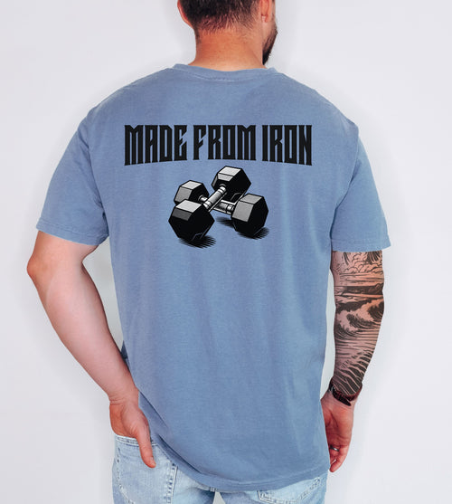 Person wearing a blue jean T-shirt with a bold back design that reads “Made From Iron” in strong, block lettering above an illustration of two black dumbbells. The graphic captures a powerful, fitness-inspired aesthetic, perfect for gym enthusiasts, weightlifters, and strength training fans who want to showcase their dedication and passion for lifting.