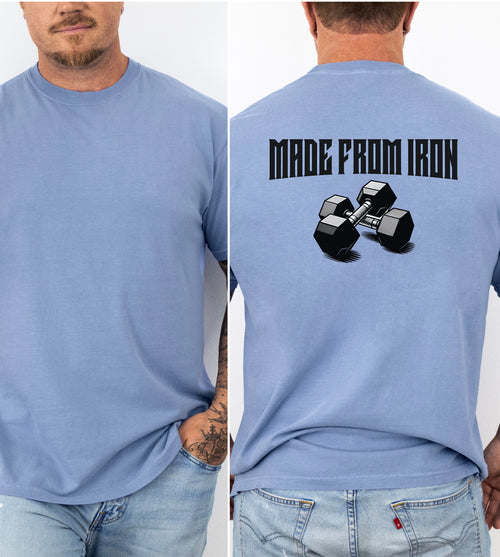 Person wearing a washed denim T-shirt with a bold back design that reads “Made From Iron” in strong, block lettering above an illustration of two black dumbbells. The graphic captures a powerful, fitness-inspired aesthetic, perfect for gym enthusiasts, weightlifters, and strength training fans who want to showcase their dedication and passion for lifting.