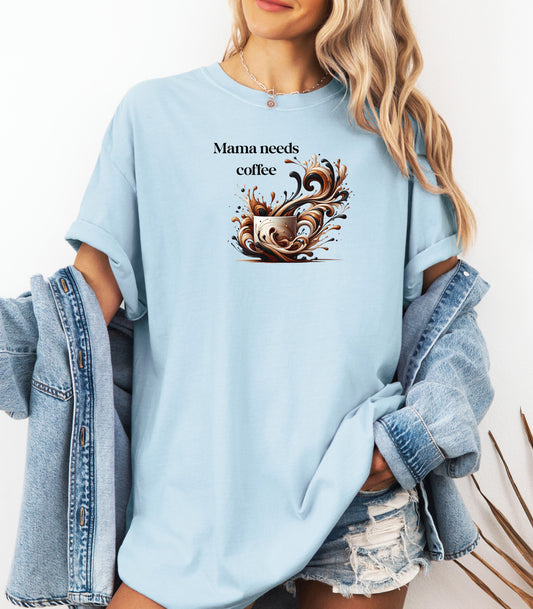 Artistic Chambray light blue t-shirt design featuring a white coffee cup surrounded by dynamic swirls of coffee, cream, and espresso in rich browns and blacks. Bold and expressive "Mama need coffee" text this design captures the energy and chaos of caffeine cravings—perfect for moms who run on coffee and need a stylish way to show it.