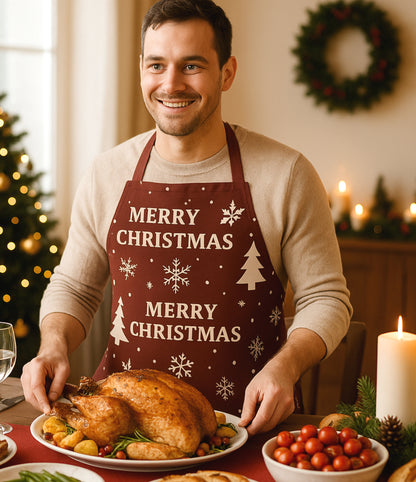 Dark red Christmas apron with white snowflakes, trees, reindeer, and festive text reading “Merry Christmas,” perfect for holiday baking and cooking.