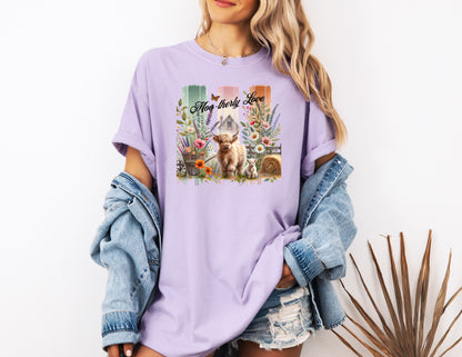 Orchid “Moo-therly Love” T-shirt featuring a charming highland cow with her calf, surrounded by colorful wildflowers, greenery, and rustic farm elements. The background showcases three vertical distressed panels in green, cream, and orange, with a quaint barn and butterfly detail. This soft, casual tee blends country charm with sweet, pastoral style, perfect for animal lovers and farm-inspired fashion.