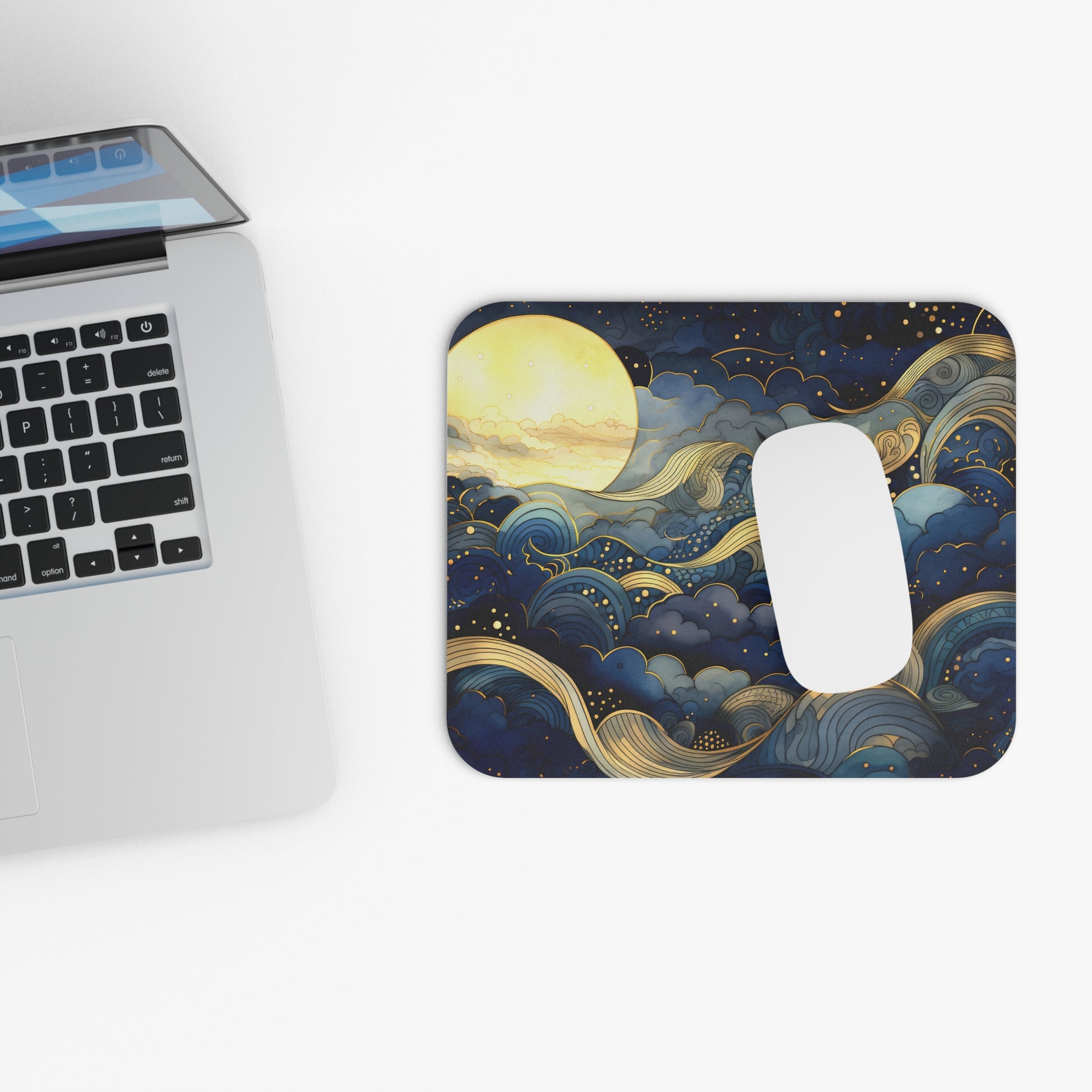 Mouse pad with celestial design next to a laptop on a white surface