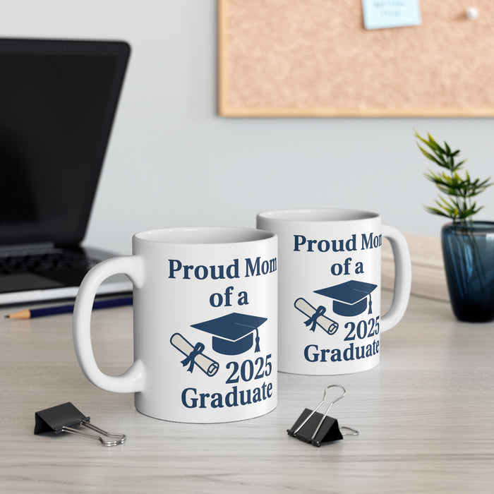 Two white mugs with 'Proud Mom of a 2025 Graduate' text, a diploma, and a graduation cap sitting on a desk with office supplies.