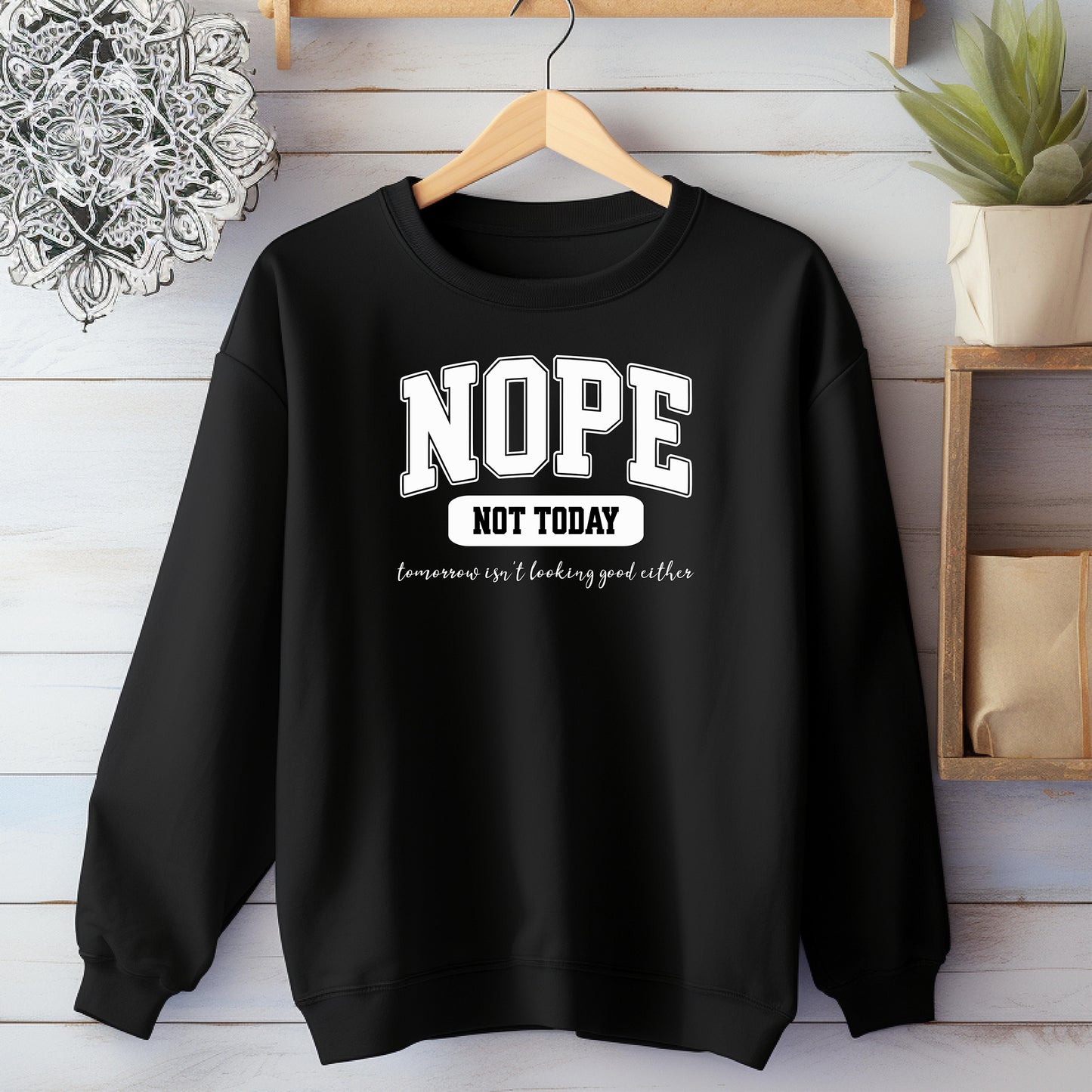 An Black sweatshirt with bold white text reading “NOPE NOT TODAY” and smaller script “tomorrow isn’t looking good either,” a humorous casual design for lazy days.