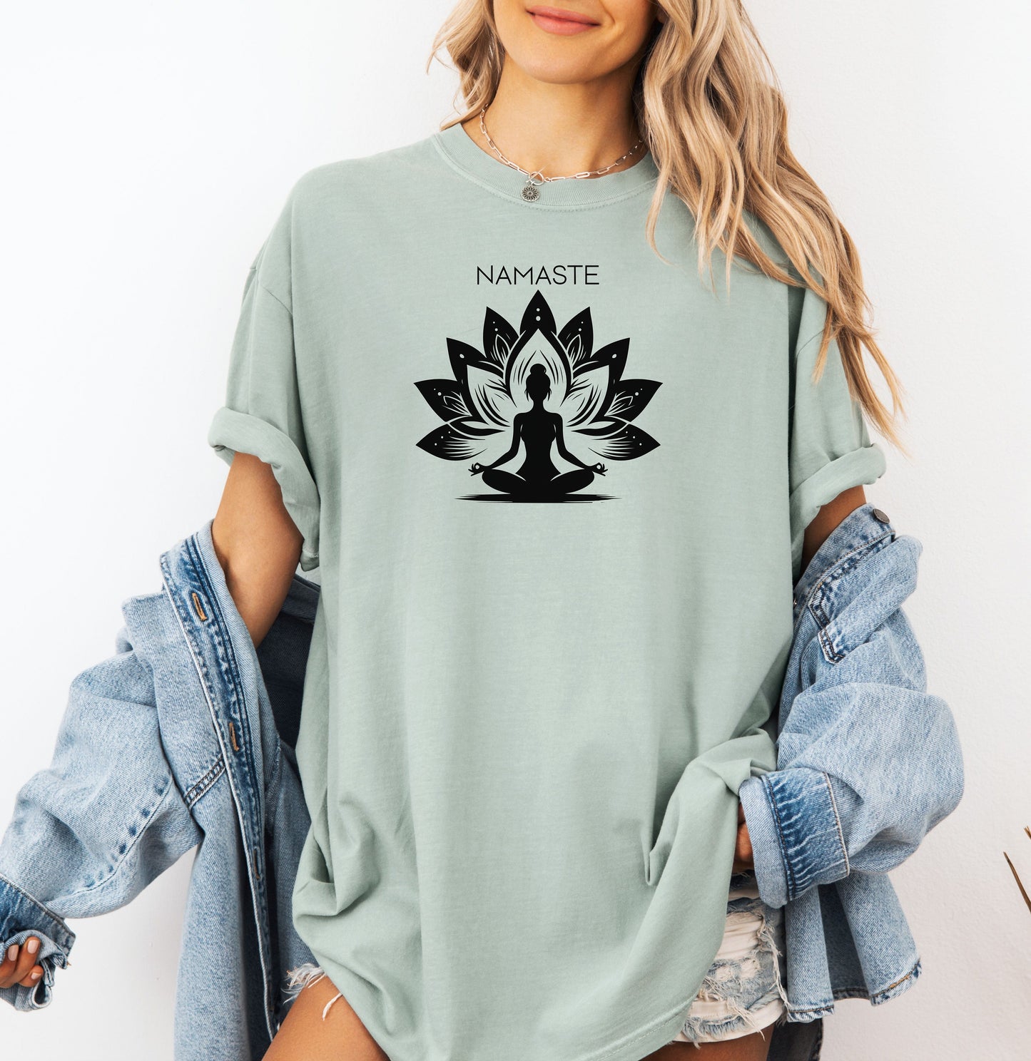 Namaste T-shirt featuring a serene yoga-inspired design with a silhouette of a person meditating in a lotus pose. Behind the figure is a stylized lotus flower, symbolizing peace, balance, and mindfulness. Printed on a soft, relaxed unisex tee, this calming graphic is perfect for yoga lovers, meditation enthusiasts, and anyone embracing a mindful lifestyle focused on inner peace and spiritual wellness.