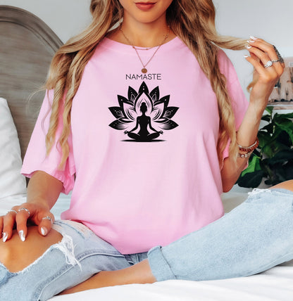 Namaste T-shirt featuring a serene yoga-inspired design with a silhouette of a person meditating in a lotus pose. Behind the figure is a stylized lotus flower, symbolizing peace, balance, and mindfulness. Printed on a soft, relaxed unisex tee, this calming graphic is perfect for yoga lovers, meditation enthusiasts, and anyone embracing a mindful lifestyle focused on inner peace and spiritual wellness.