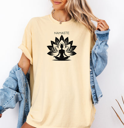 Namaste T-shirt featuring a serene yoga-inspired design with a silhouette of a person meditating in a lotus pose. Behind the figure is a stylized lotus flower, symbolizing peace, balance, and mindfulness. Printed on a soft, relaxed unisex tee, this calming graphic is perfect for yoga lovers, meditation enthusiasts, and anyone embracing a mindful lifestyle focused on inner peace and spiritual wellness.