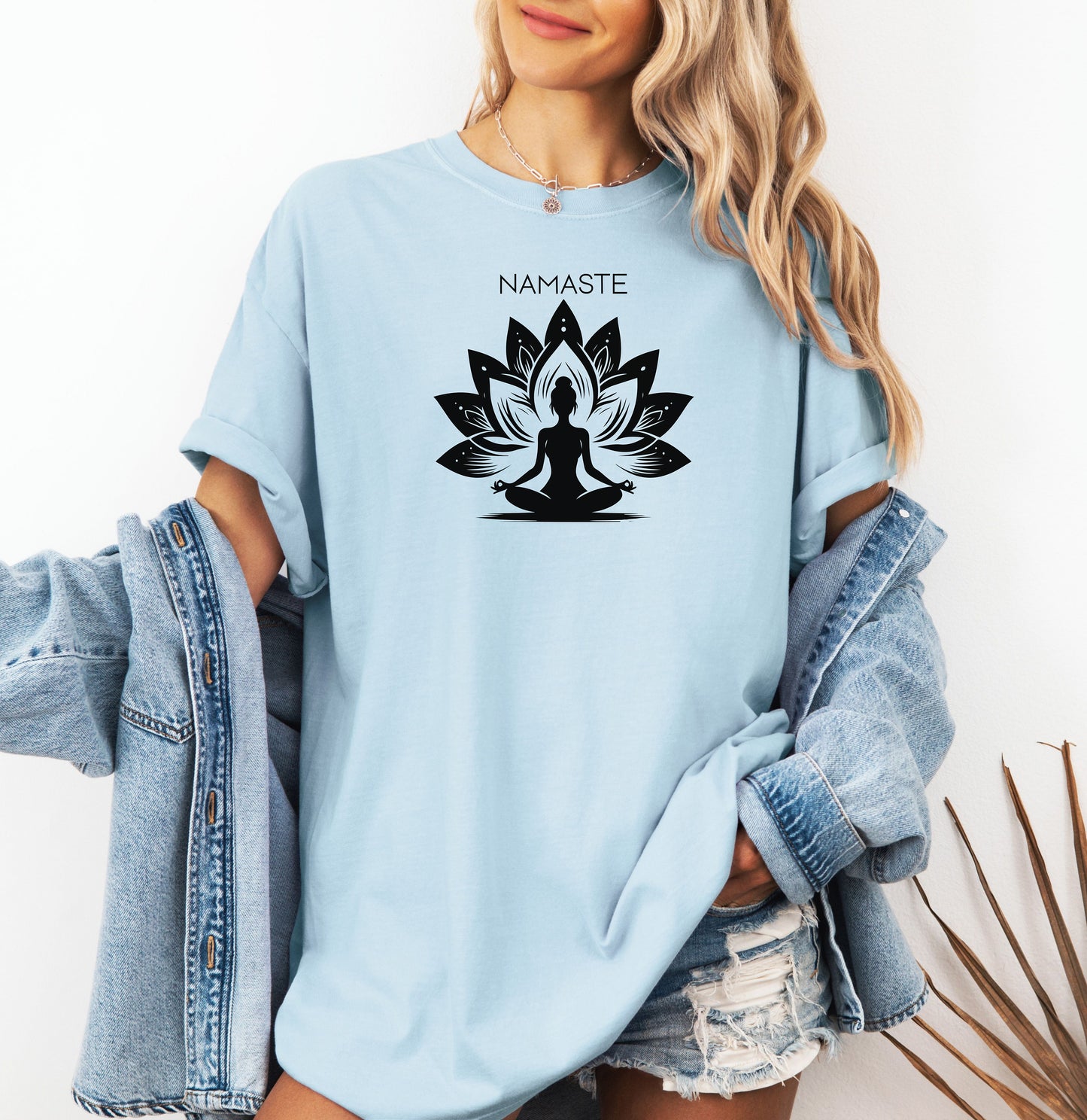Namaste T-shirt featuring a serene yoga-inspired design with a silhouette of a person meditating in a lotus pose. Behind the figure is a stylized lotus flower, symbolizing peace, balance, and mindfulness. Printed on a soft, relaxed unisex tee, this calming graphic is perfect for yoga lovers, meditation enthusiasts, and anyone embracing a mindful lifestyle focused on inner peace and spiritual wellness.