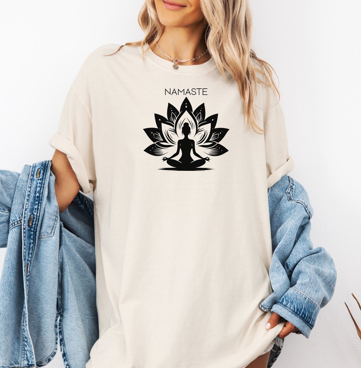 Namaste T-shirt featuring a serene yoga-inspired design with a silhouette of a person meditating in a lotus pose. Behind the figure is a stylized lotus flower, symbolizing peace, balance, and mindfulness. Printed on a soft, relaxed unisex tee, this calming graphic is perfect for yoga lovers, meditation enthusiasts, and anyone embracing a mindful lifestyle focused on inner peace and spiritual wellness.