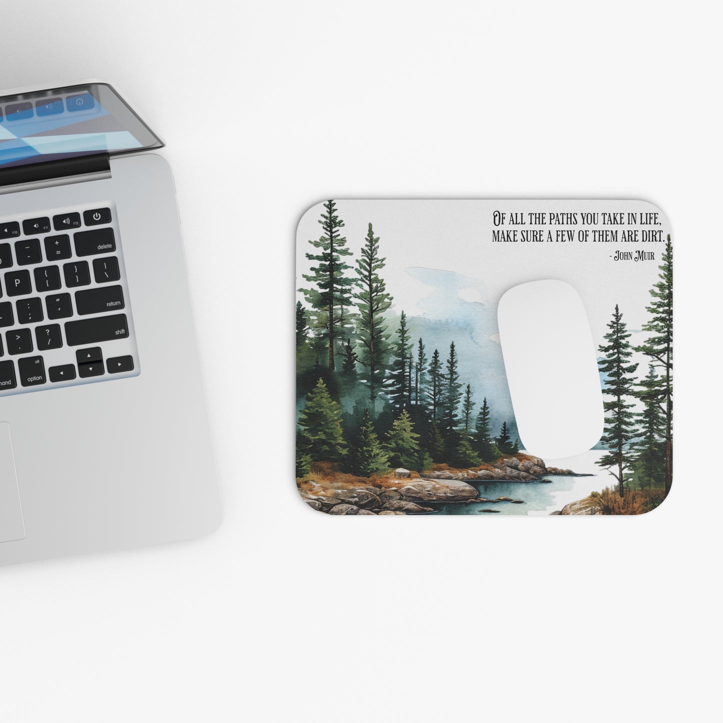 Laptop with a scenic mouse pad featuring a forest design and a John Muir quote.