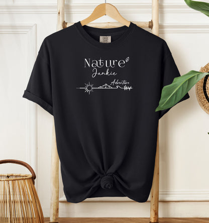 Nature Junkie T-shirt with minimalist white line art showing a sun, mountains, trees, and the words 'Nature Junkie Adventure' with a small leaf accent. Printed on a soft black unisex Comfort Colors tee, perfect for outdoor lovers, hikers, campers, and those who enjoy exploring nature and adventure.