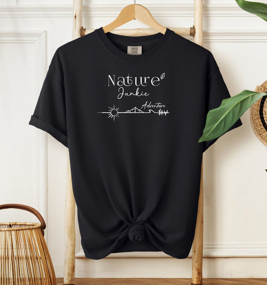 Nature Junkie T-shirt with minimalist white line art showing a sun, mountains, trees, and the words 'Nature Junkie Adventure' with a small leaf accent. Printed on a soft black unisex Comfort Colors tee, perfect for outdoor lovers, hikers, campers, and those who enjoy exploring nature and adventure.