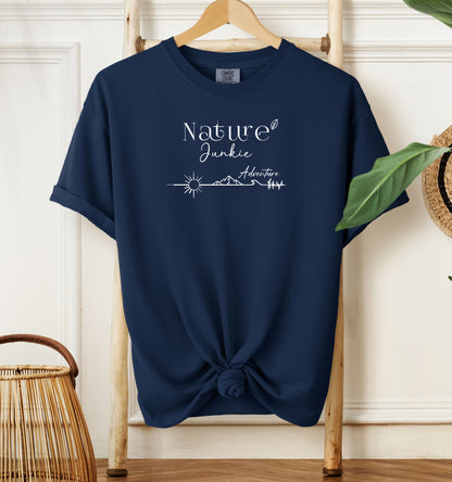 Nature Junkie T-shirt with minimalist white line art showing a sun, mountains, trees, and the words 'Nature Junkie Adventure' with a small leaf accent. Printed on a soft true navy unisex Comfort Colors tee, perfect for outdoor lovers, hikers, campers, and those who enjoy exploring nature and adventure.