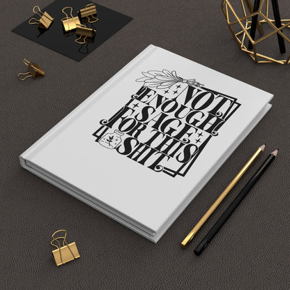 Hardcover Journal with black text design on a dark surface with office supplies.