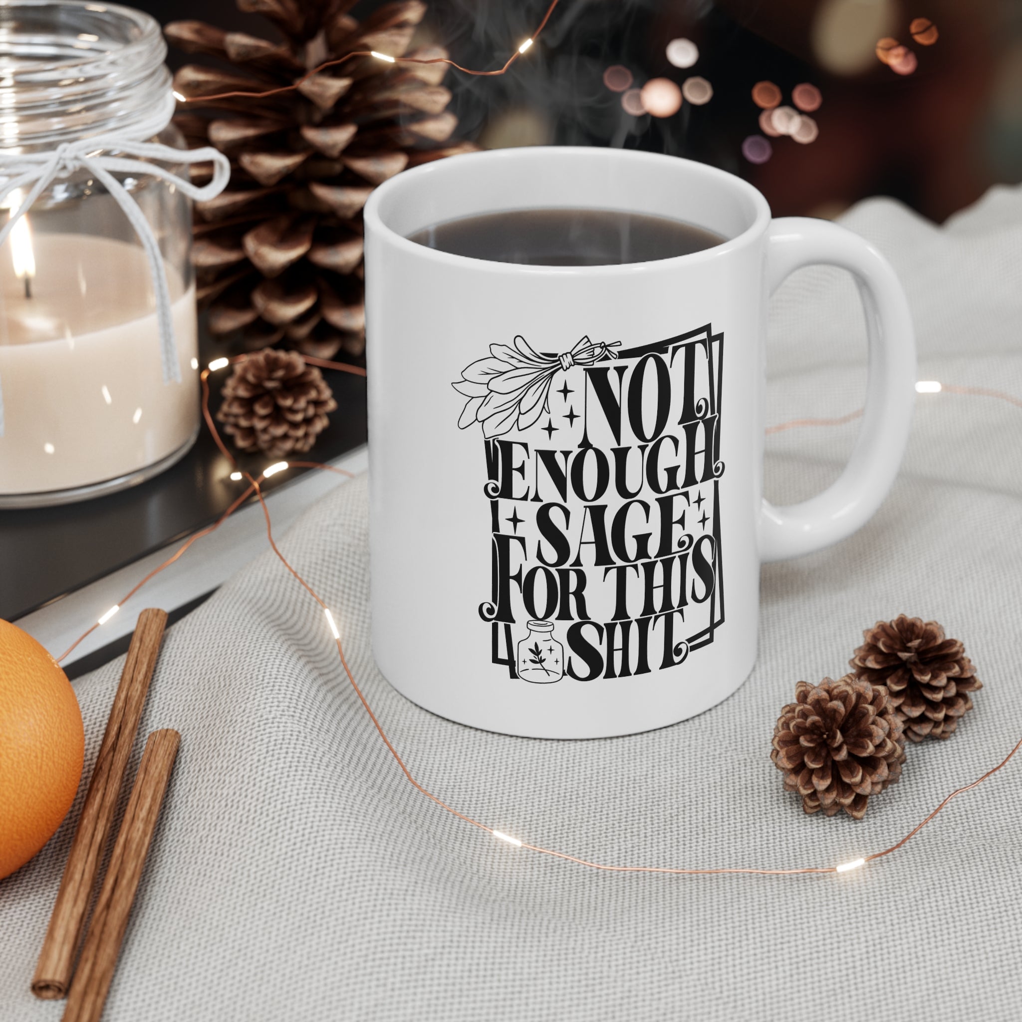 White ceramic mug featuring bold black typography reading “Not Enough Sage For This Shit,” framed in a whimsical outlined border. The design includes a detailed sage bundle illustration at the top and a small jar with a sage leaf motif at the bottom, adding a witchy, mystical vibe. Perfect for humorous coffee or tea moments, it blends sassy attitude with boho and spiritual flair, making it an ideal gift for friends with a sense of humor.