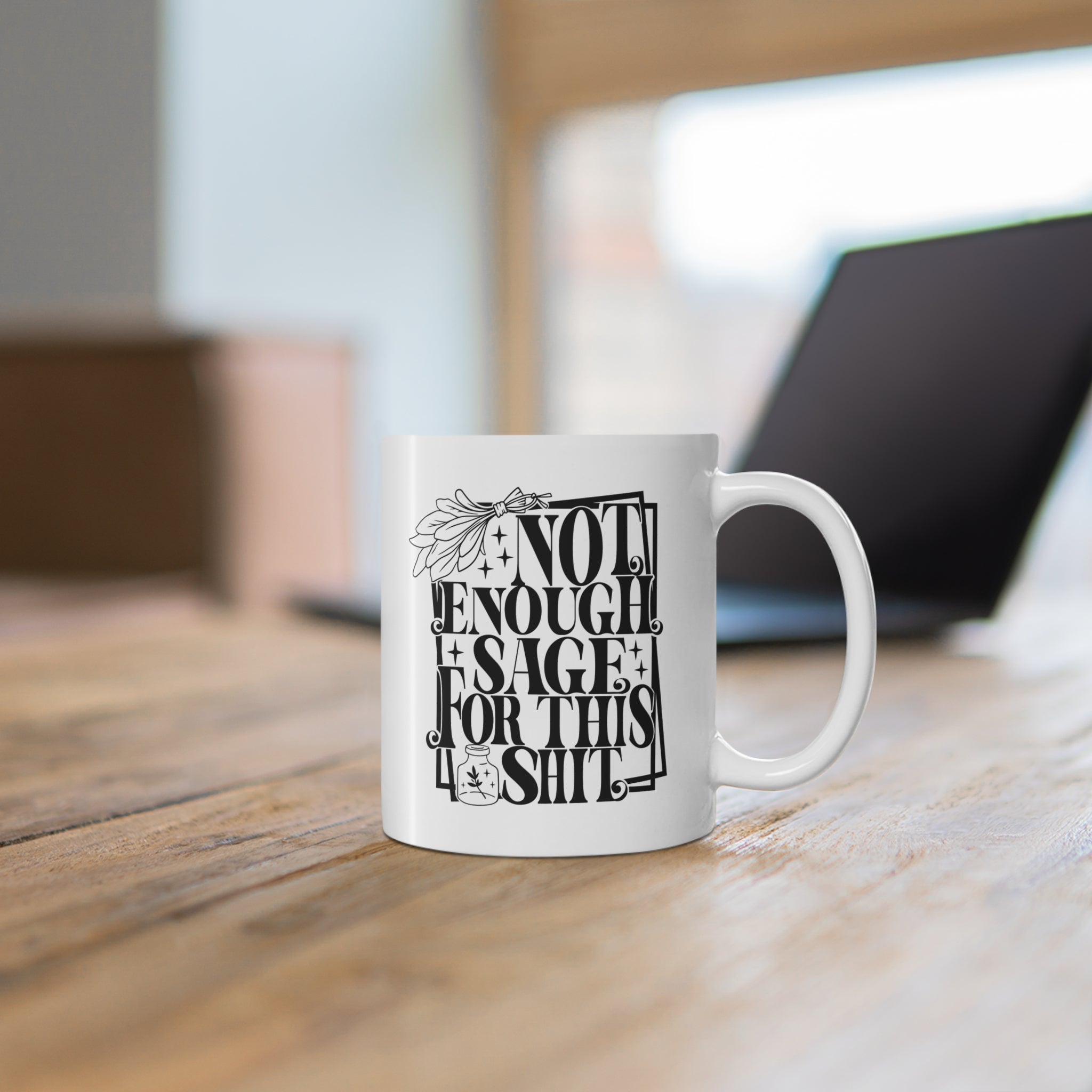 White ceramic mug featuring bold black typography reading “Not Enough Sage For This Shit,” framed in a whimsical outlined border. The design includes a detailed sage bundle illustration at the top and a small jar with a sage leaf motif at the bottom, adding a witchy, mystical vibe. Perfect for humorous coffee or tea moments, it blends sassy attitude with boho and spiritual flair, making it an ideal gift for friends with a sense of humor.