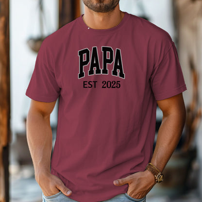 PAPA Est [Year] T-shirt featuring bold collegiate-style lettering with a customizable establishment year. Printed on a soft, relaxed-fit unisex tee in a chili color, this design makes a perfect gift for new grandfathers, Father’s Day, or family celebrations. Ideal for proudly announcing the year someone became 'Papa' while offering comfort and casual style.