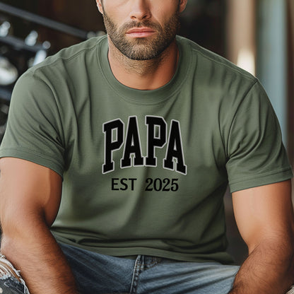 PAPA Est [Year] T-shirt featuring bold collegiate-style lettering with a customizable establishment year. Printed on a soft, relaxed-fit unisex tee in a moss color, this design makes a perfect gift for new grandfathers, Father’s Day, or family celebrations. Ideal for proudly announcing the year someone became 'Papa' while offering comfort and casual style.
