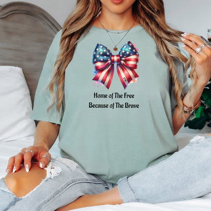Bay light sage t-shirt featuring a patriotic coquette bow design with stars and stripes in red, white, and blue. Below the bow, the text reads 'Home of The Free Because of The Brave.' A stylish and feminine Holiday shirt, perfect for celebrating Independence Day, parades, and summer festivities.