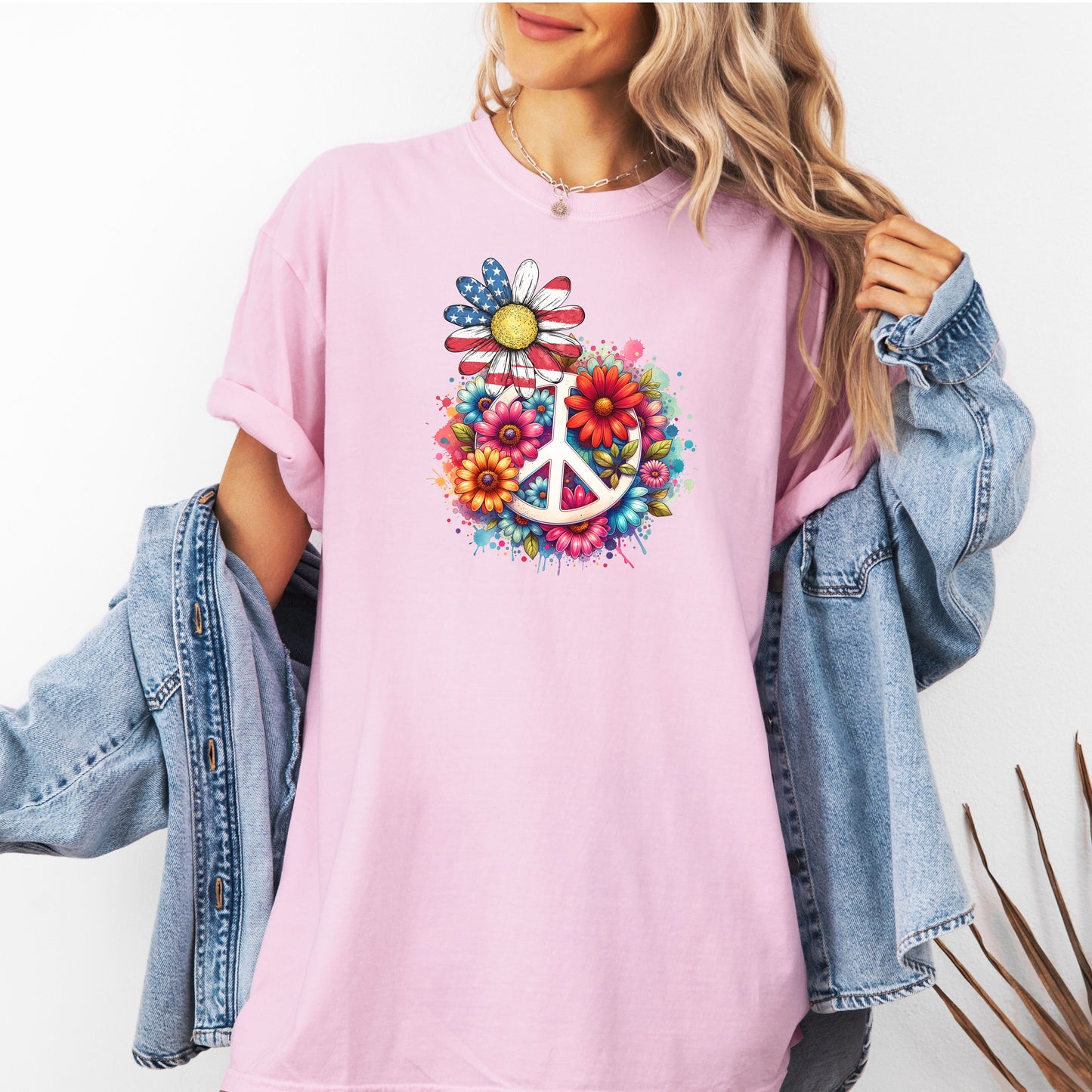 Blossom pink t-shirt featuring a vibrant retro Peace Love Liberty design with a large white peace sign surrounded by colorful flowers. A daisy with red, white, and blue American flag petals stands out, blending patriotic style with boho hippie vibes. Perfect for 4th of July, festivals, and casual summer wear.