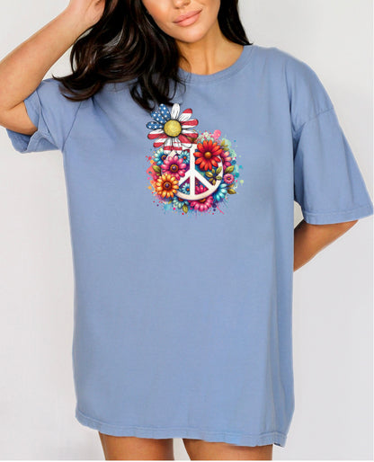 Washed Denim t-shirt featuring a vibrant retro Peace Love Liberty design with a large white peace sign surrounded by colorful flowers. A daisy with red, white, and blue American flag petals stands out, blending patriotic style with boho hippie vibes. Perfect for 4th of July, festivals, and casual summer wear.