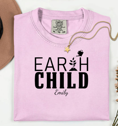 Personalized Earth Child T-shirt featuring a stylish nature-inspired design. The shirt displays the words 'EARTH CHILD' with a plant sprouting from the letter T being watered by a small watering can, symbolizing growth and love for nature. Customizable with a name below the text, this soft, casual unisex tee is perfect for eco-conscious individuals, gardeners, and free spirits who embrace a sustainable and earthy lifestyle.