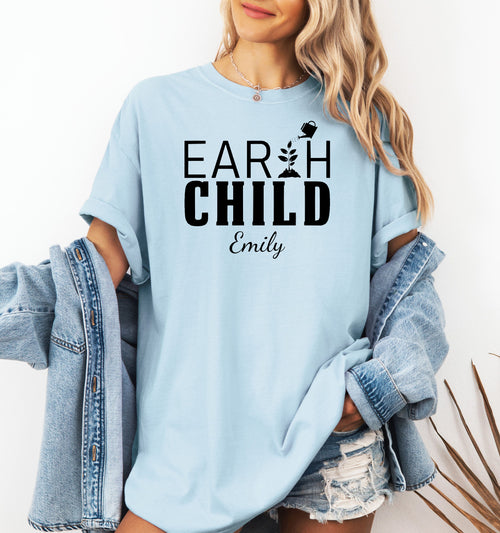 Personalized Earth Child T-shirt featuring a stylish nature-inspired design. The shirt displays the words 'EARTH CHILD' with a plant sprouting from the letter T being watered by a small watering can, symbolizing growth and love for nature. Customizable with a name below the text, this soft, casual unisex tee is perfect for eco-conscious individuals, gardeners, and free spirits who embrace a sustainable and earthy lifestyle.