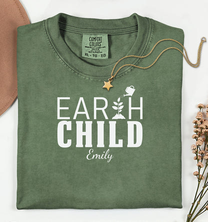Personalized Earth Child T-shirt featuring a stylish nature-inspired design. The shirt displays the words 'EARTH CHILD' with a plant sprouting from the letter T being watered by a small watering can, symbolizing growth and love for nature. Customizable with a name below the text, this soft, casual unisex tee is perfect for eco-conscious individuals, gardeners, and free spirits who embrace a sustainable and earthy lifestyle.