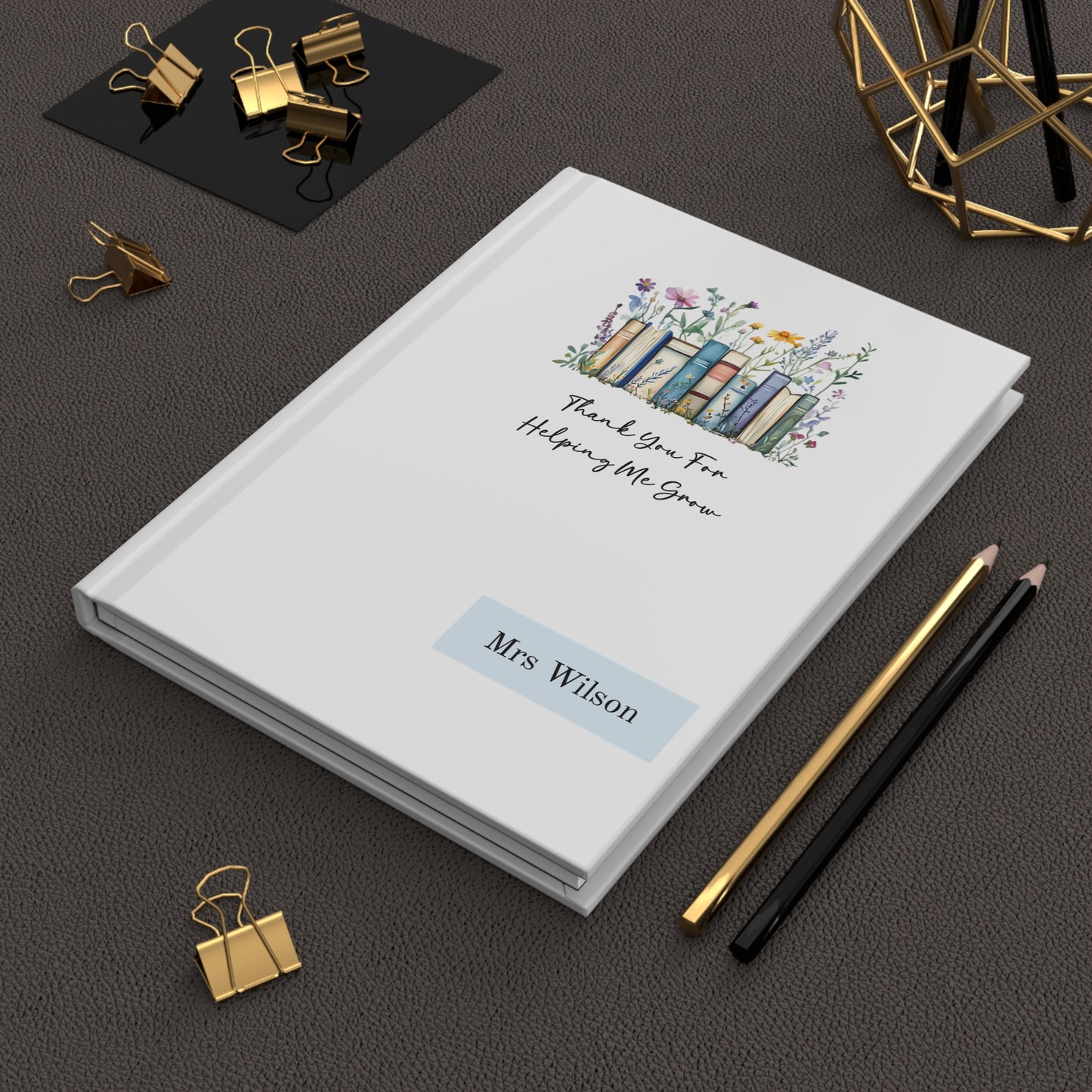 Personalized hardcover journal with decorative cover on a dark surface with stationery items.
