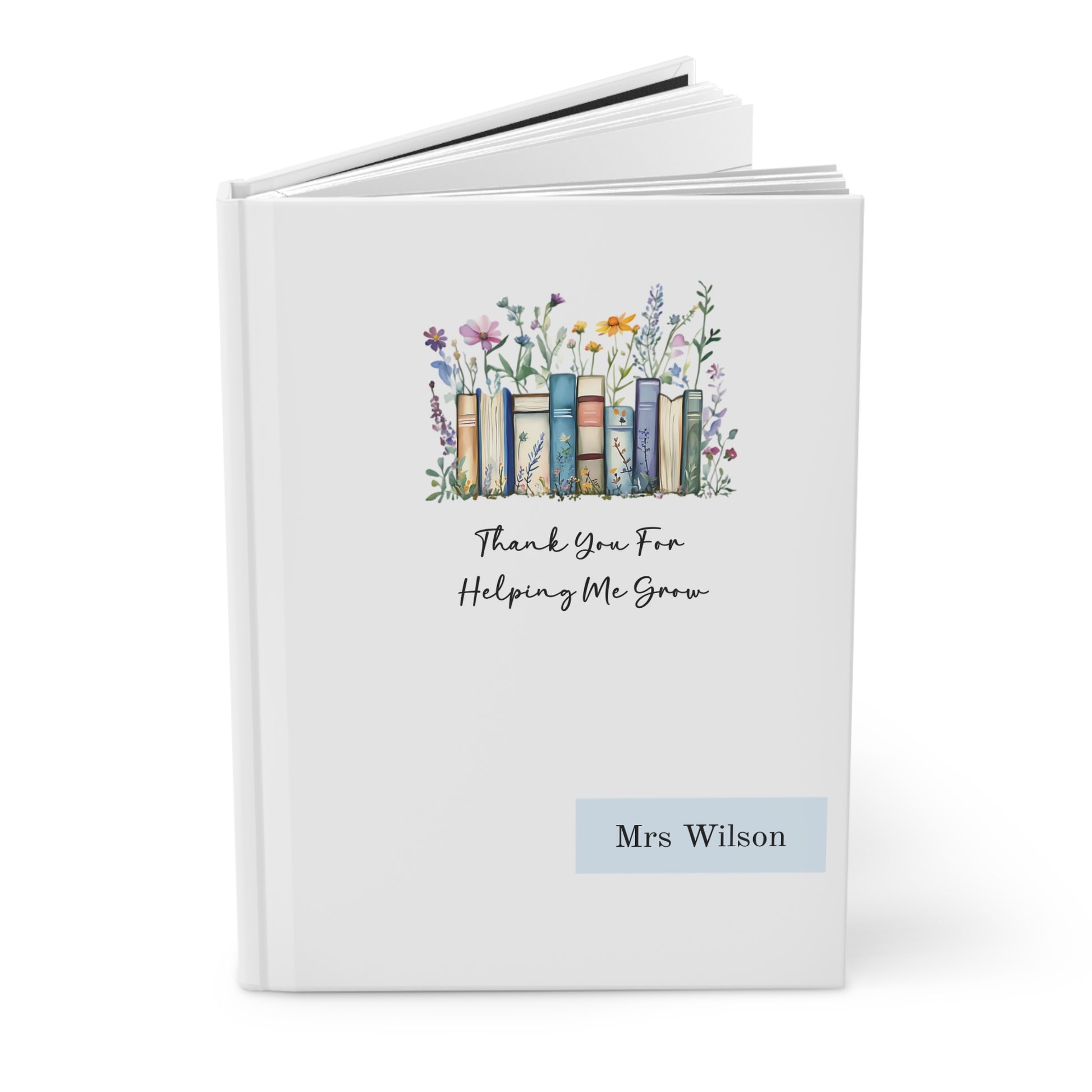 Open hardcover journal with floral design, books, and text on a white background