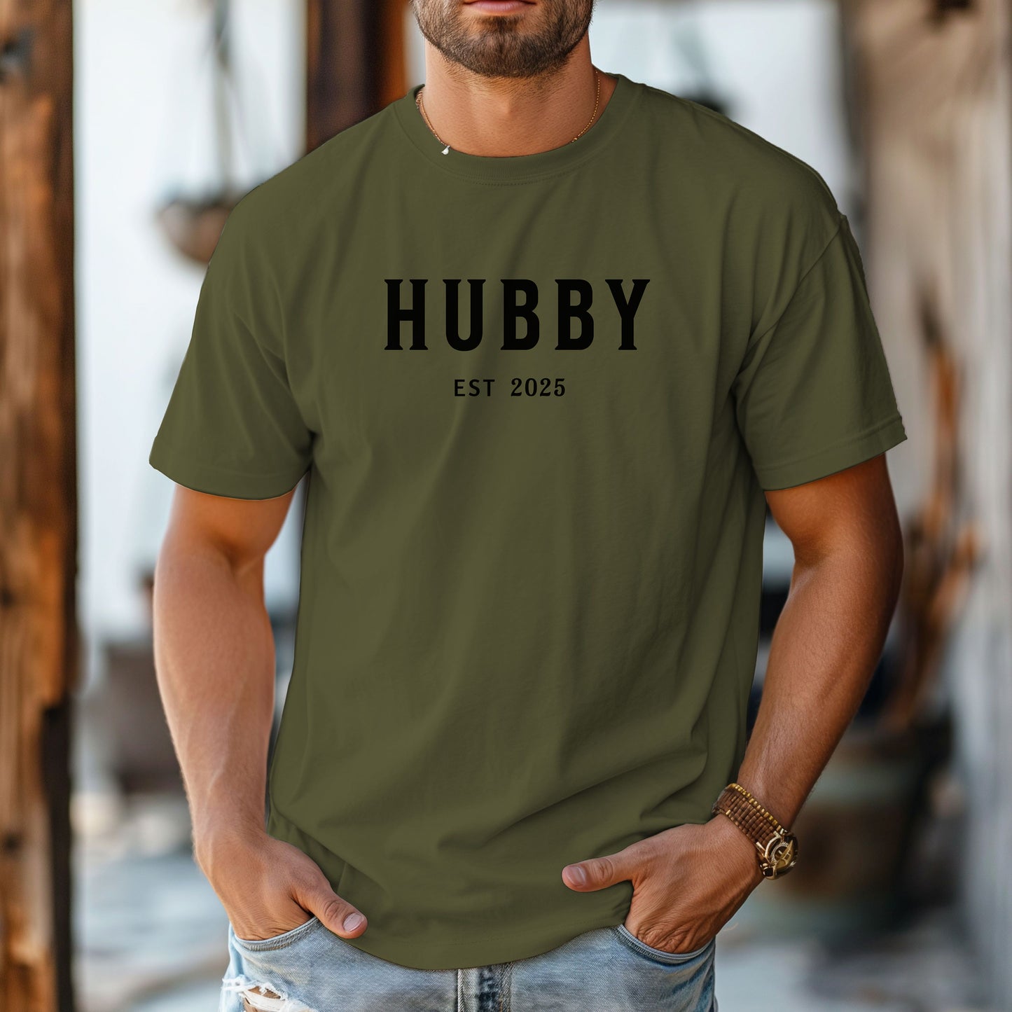 Hubby Est [Year] design printed on a Hemp color unisex t-shirt. The shirt features bold black capital letters spelling 'HUBBY' with 'EST [Year]' in smaller text below. Perfect for newlyweds, anniversaries, or wedding gifts, this casual and modern design celebrates marriage in a simple, stylish way. 