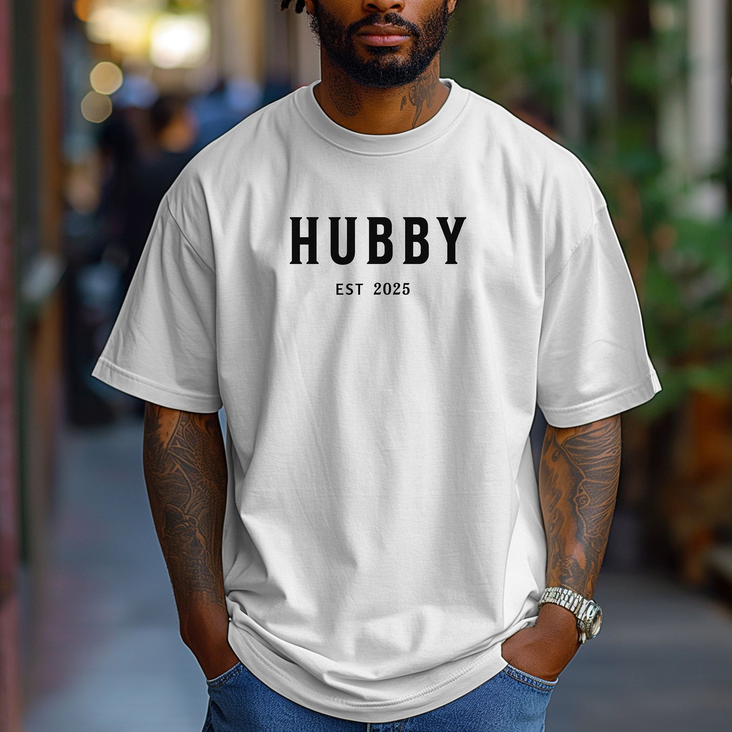 Hubby Est [Year] design printed on a White unisex t-shirt. The shirt features bold black capital letters spelling 'HUBBY' with 'EST [Year]' in smaller text below. Perfect for newlyweds, anniversaries, or wedding gifts, this casual and modern design celebrates marriage in a simple, stylish way. 