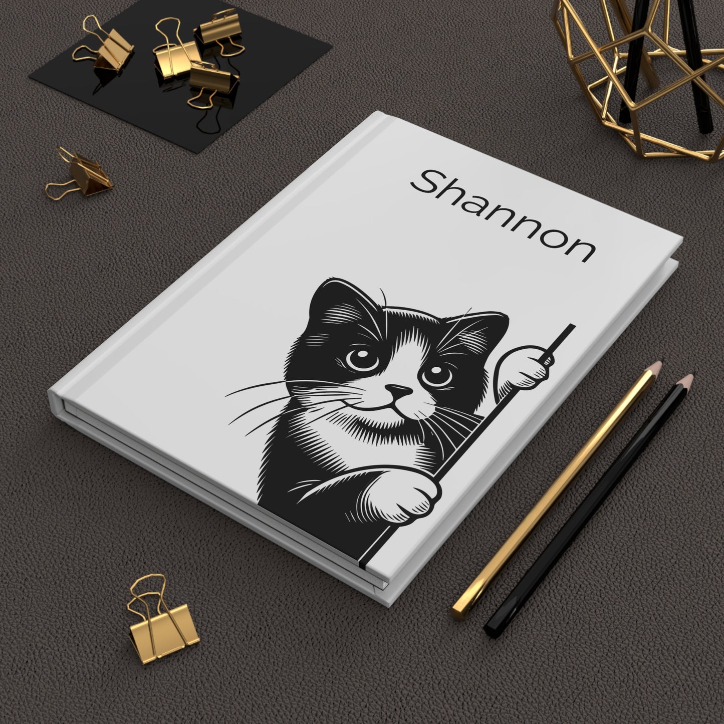 Personalized  Peeking Kittens Hardcover Journal a black and white cat illustration and the name on a dark surface with office supplies.