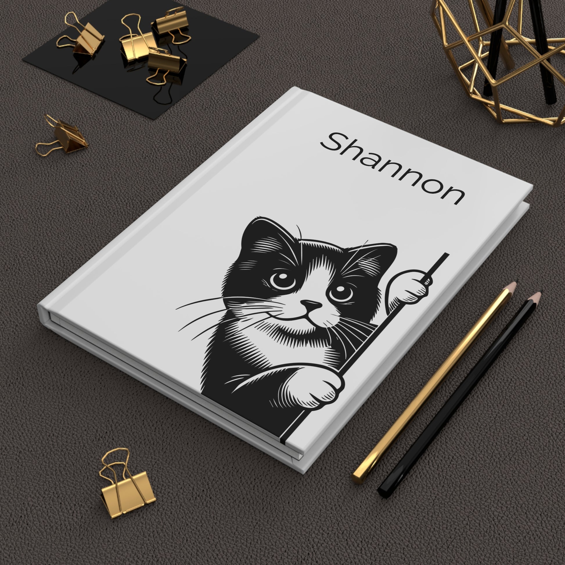 Personalized  Peeking Kittens Hardcover Journal a black and white cat illustration and the name on a dark surface with office supplies.