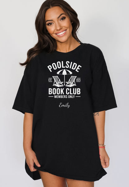 Person wearing a Black T-shirt featuring a "Poolside Book Club Members Only" design with two lounge chairs and an umbrella graphic, personalized with the name you choose.