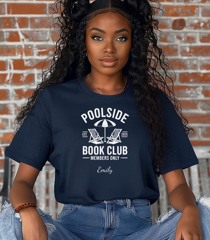 Person wearing a True Navy T-shirt featuring a "Poolside Book Club Members Only" design with two lounge chairs and an umbrella graphic, personalized with the name you choose.