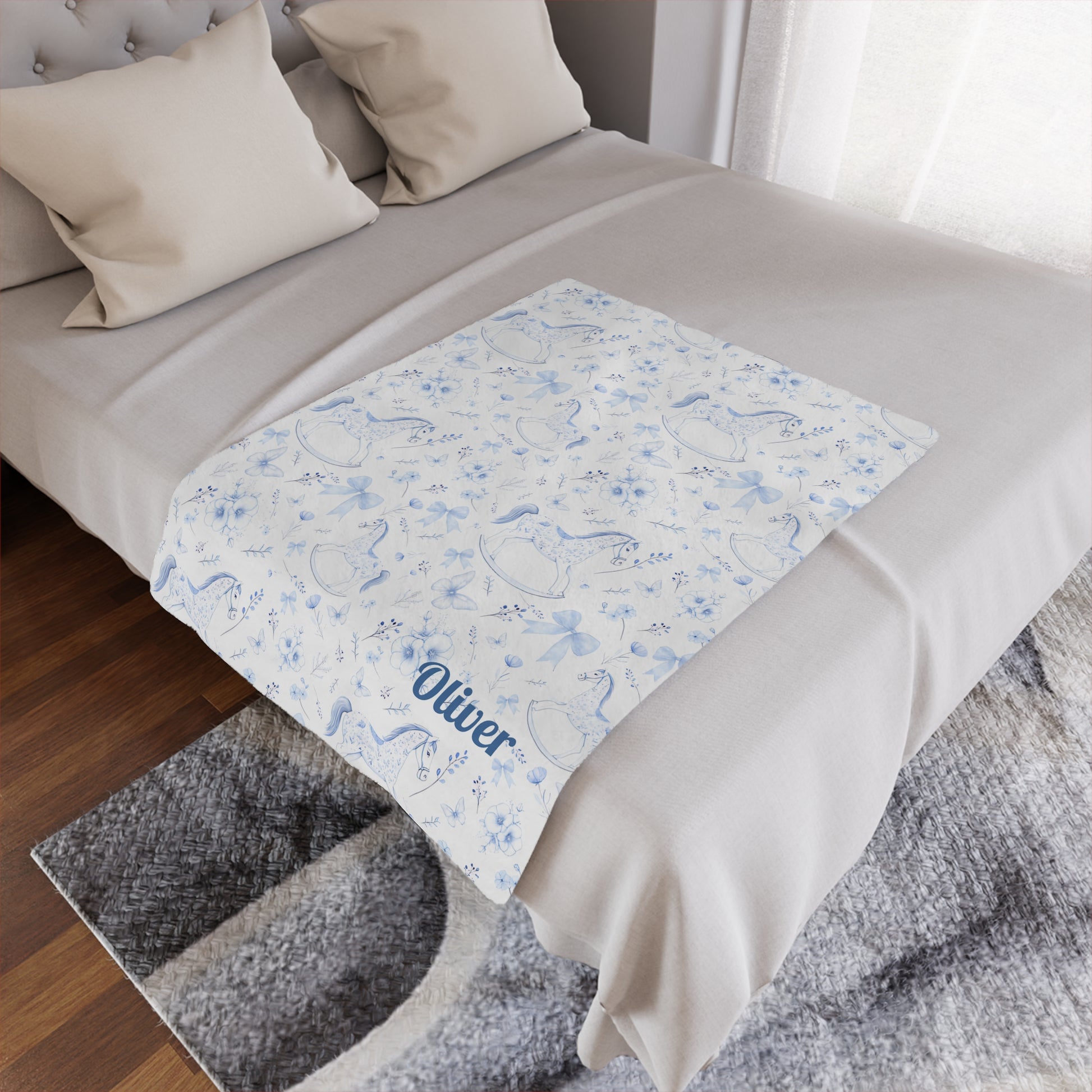 Personalized Rocking Horse Minky blanket with blue chinoiserie patterns and 'Oliver' text on a bed in a bedroom.