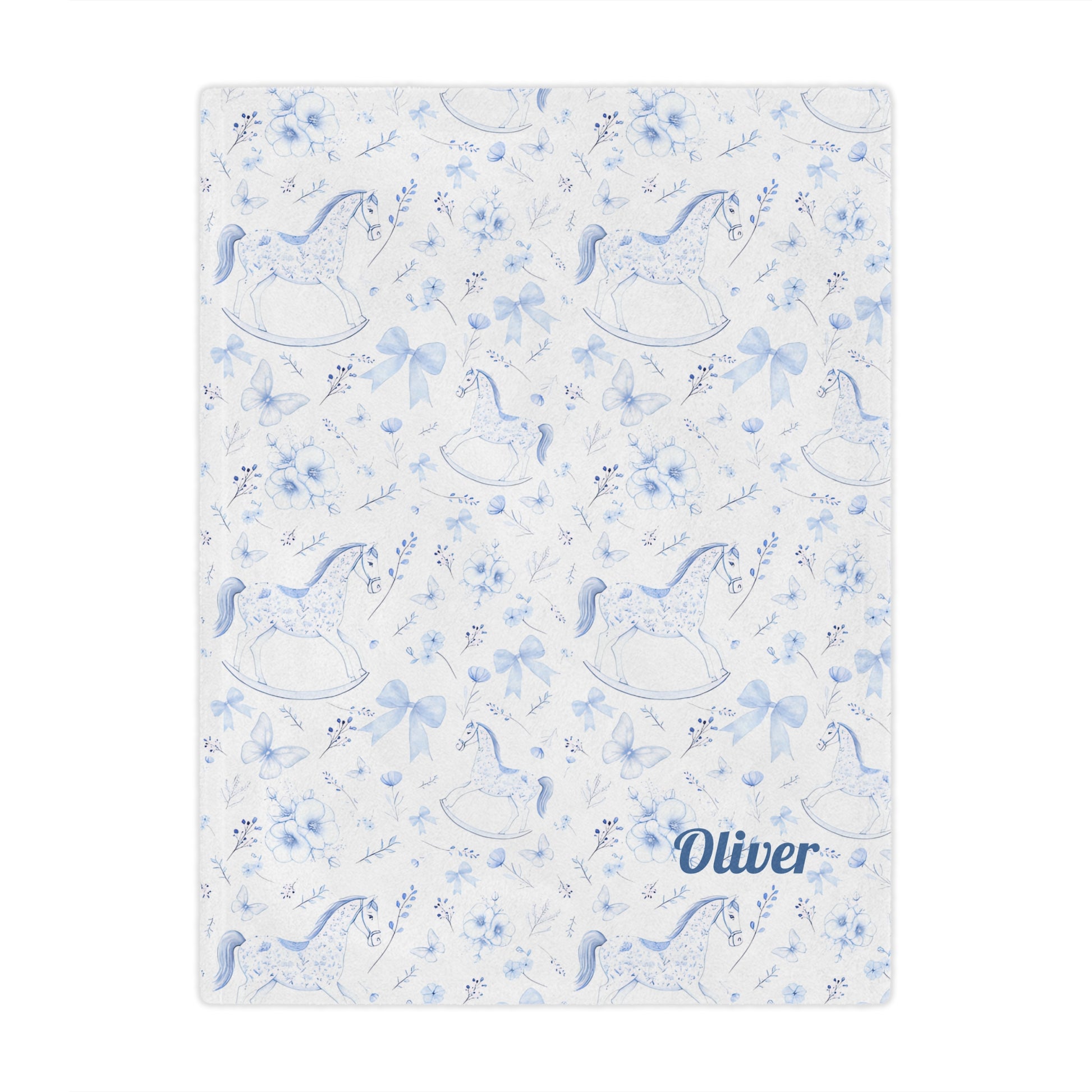 Personalized Rocking Horse Minky blanket with blue chinoiserie patterns and 'Oliver' text on a bed in a bedroom.