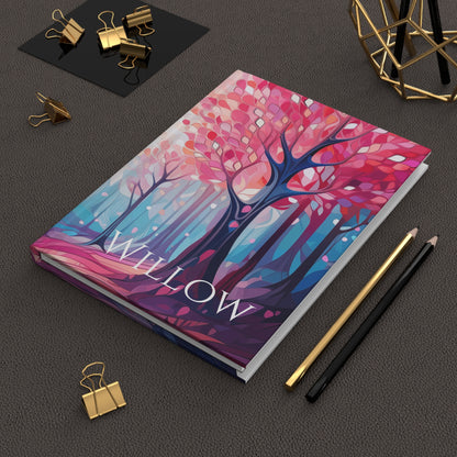 Personalized Stained Glass Forest Hardcover Journal with name design on a dark surface with stationery items.