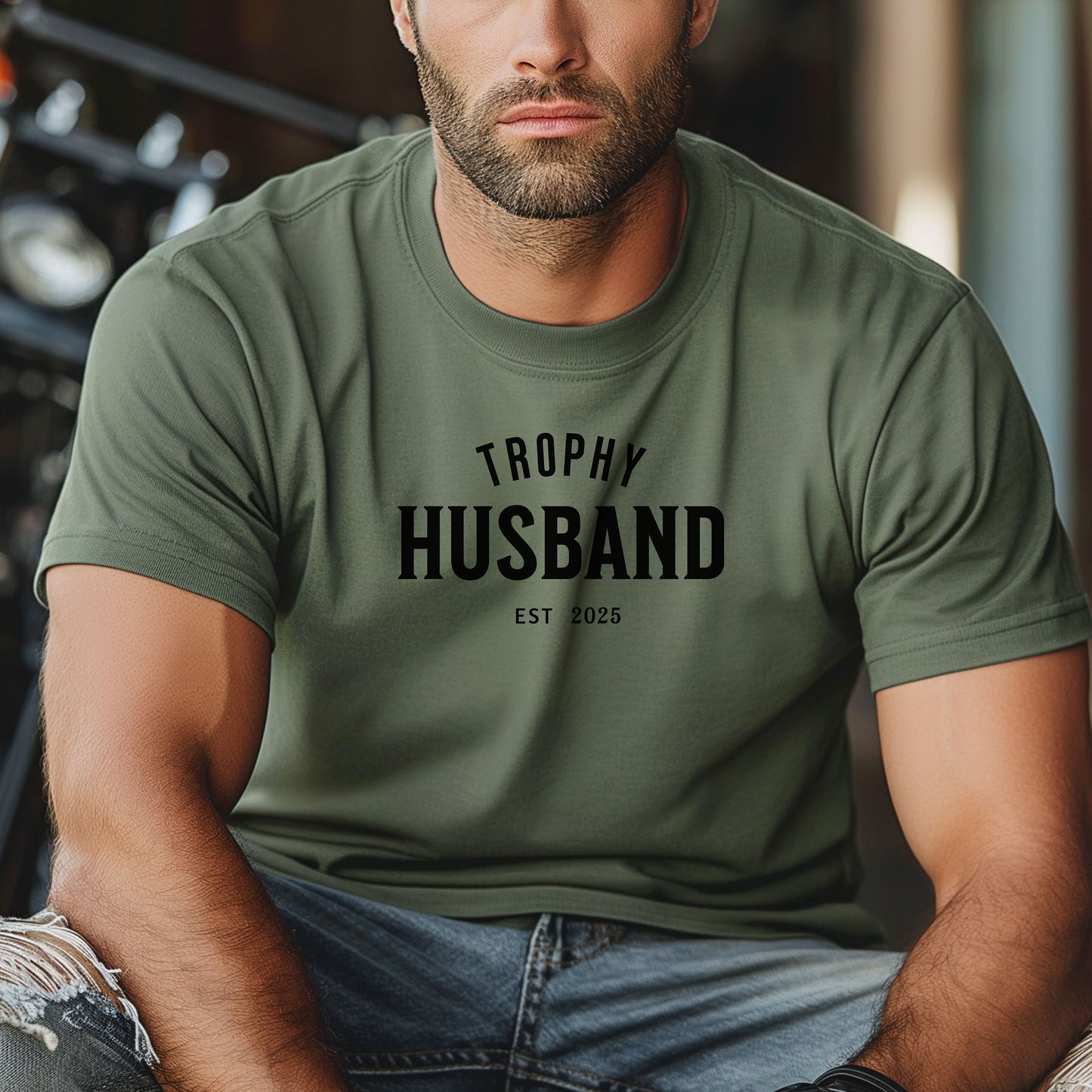 Moss Trophy Husband EST [Year] graphic T-shirt featuring bold black typography on a casual crewneck shirt. Perfect gift for newlyweds, anniversaries, grooms, or husbands with a sense of humor. Comfortable, stylish, and great for everyday wear or special occasions to celebrate marriage and fun couple vibes.